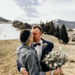 Nach der Hochzeit in den Bergen küssen sich Braut und Bräutigam. Die Braut hält dabei ihren Brautstrauß.