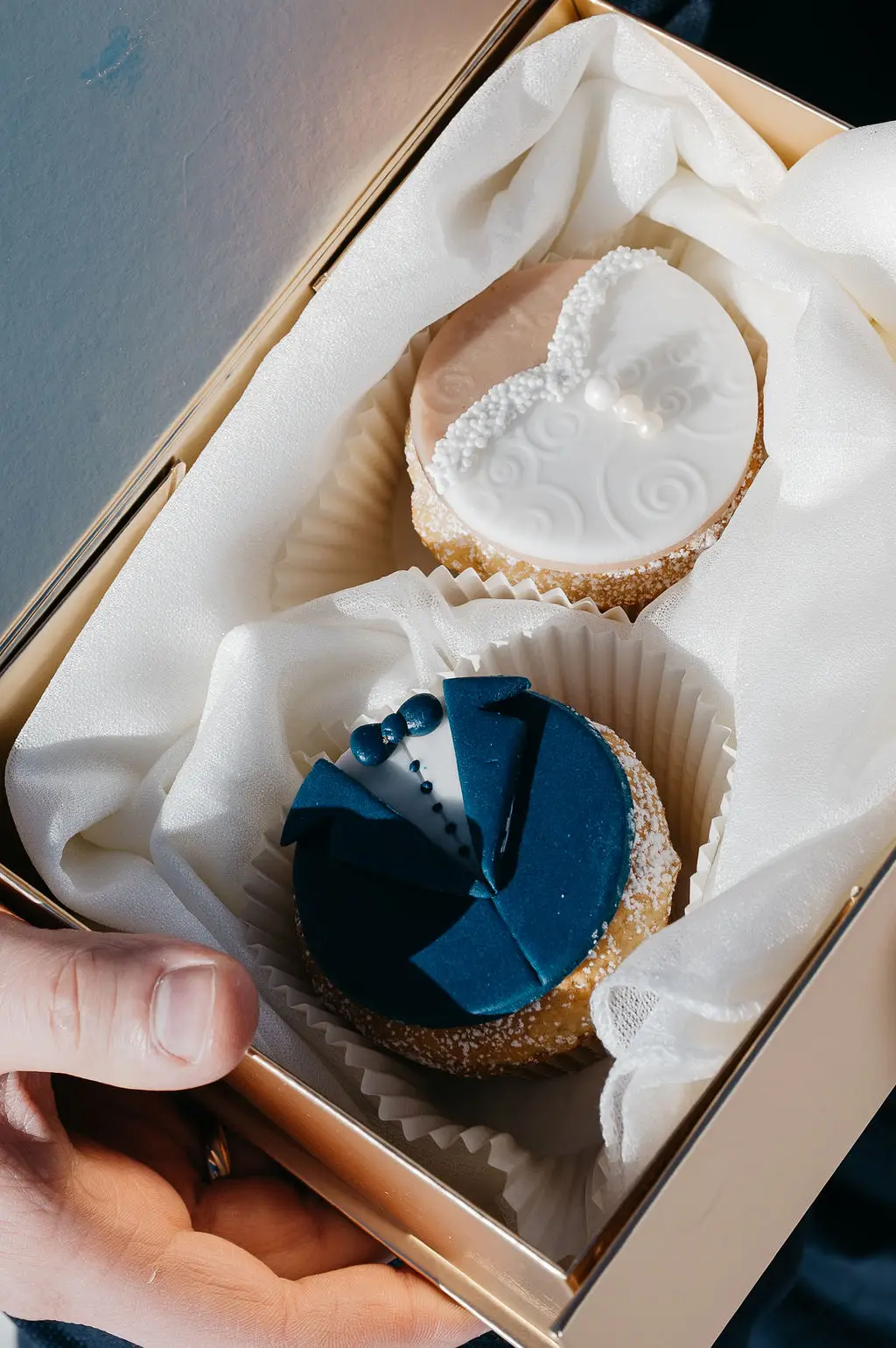 Zwei kunstvoll verzierte Cupcakes in Form eines Brautkleids und eines Anzugs – eine süße Überraschung für das Brautpaar bei einer Hochzeit am Tegernsee.