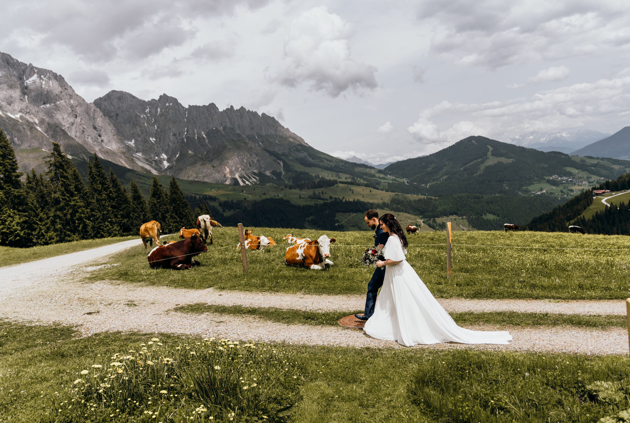 Brautpaar nach standesamtlicher Trauung auf der Alm – umgeben von Kühen, Wiesen und Bergen“