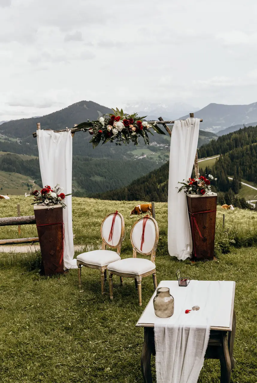 raubogen mit floraler Dekoration und zwei Stühlen bei einer standesamtlichen Trauung auf der Alm mit Blick auf die Berge